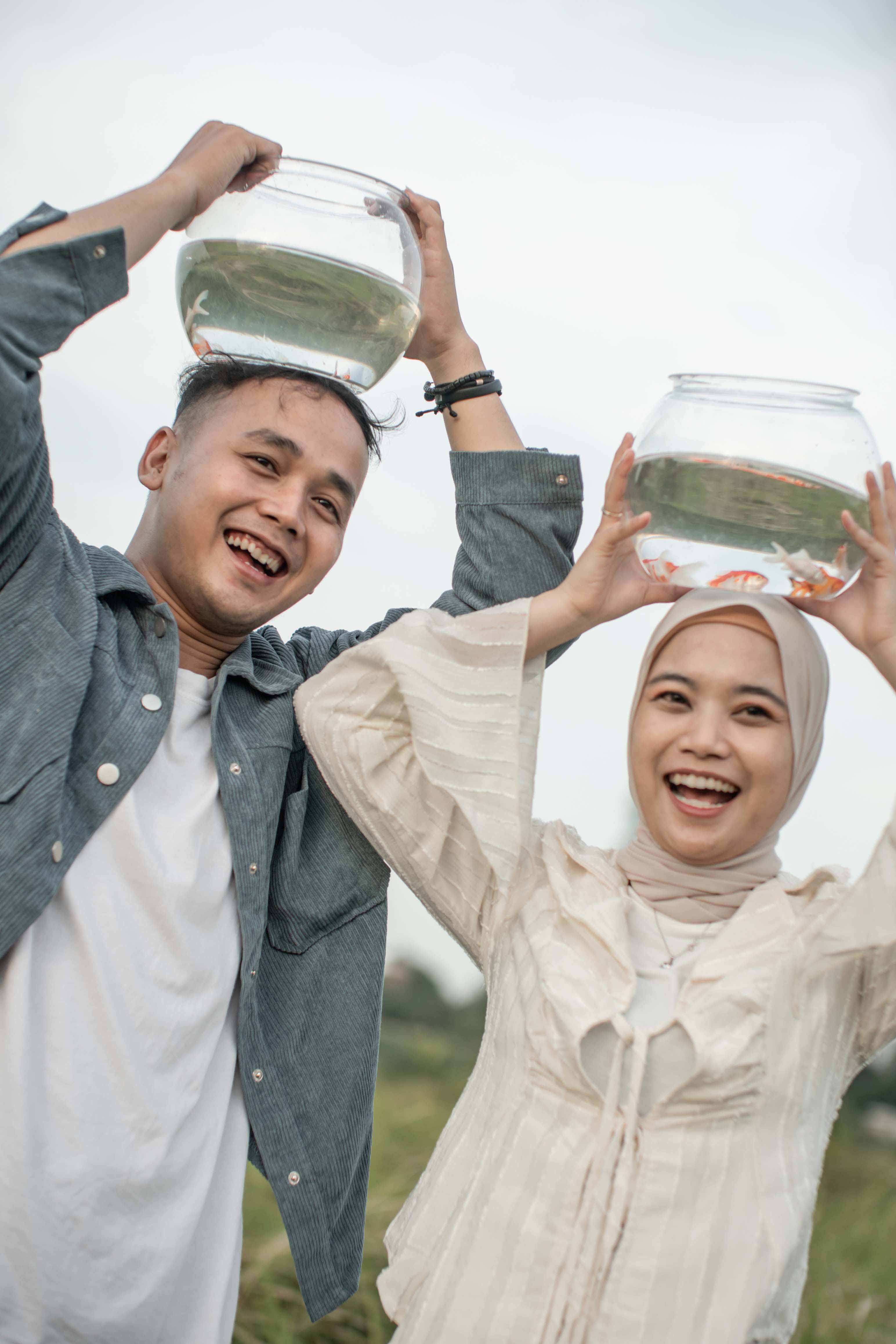 Pasangan tertawa sambil memegang mangkuk ikan